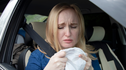 Woman sitting in a car with motion sickness and a barf bag