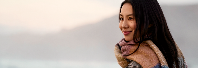 Smiling woman in a cozy scarf outdoors – herbal supplements for kidney and urinary health.
