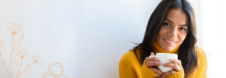 Smiling woman in a yellow sweater holding a warm mug – herbs for digestive and gut health.